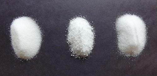 Three neat piles of sugar, sucralose and erythritol against a black surface
