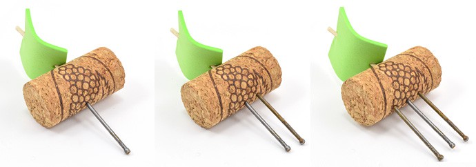 Three corks each have a toothpick and green foam inserted into one side and 1, 2 or 3 nails inserted into the opposite side