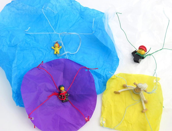 Four figurines attached to colorful tissue paper parachutes