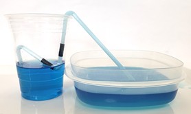 An M-shaped straw siphon transferring water from a taller cup to a shorter container. 