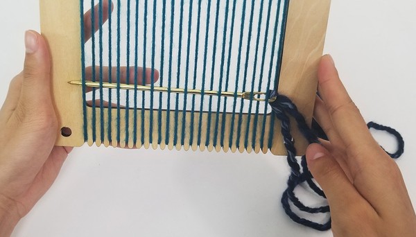 Tapestry needle weaving through warp threads 
