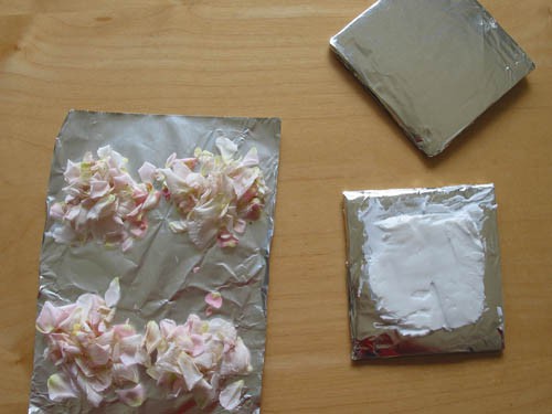 Vegetable shortening spread over an aluminum foil square next to four piles of flower petals