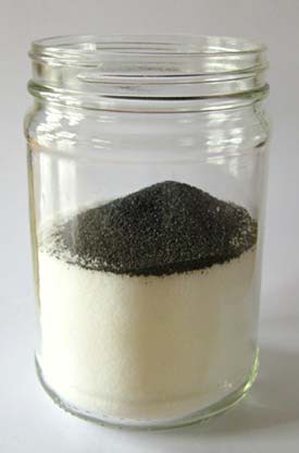 Pile of iron filings resting on salt in a glass jar