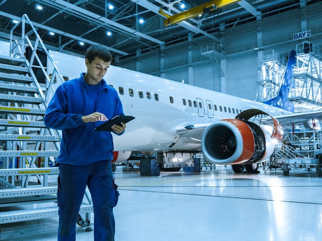 man with tablet by airplane