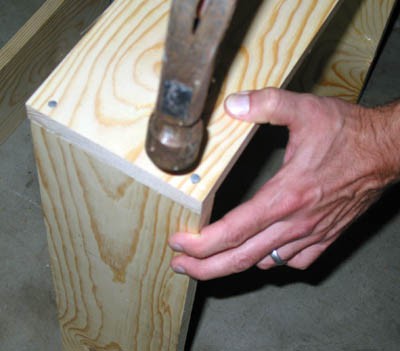 Two wooden boards are nailed together at their ends forming one corner of a box