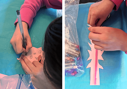 Student decorating paper elements for the toy car and preparing them with straw supports for stability