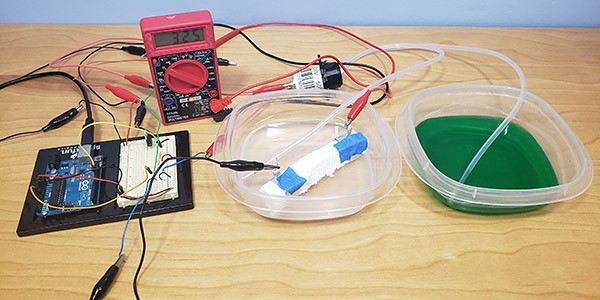 Arduino, multimeter, and two containers of water set up for artificial pancreas experiment 