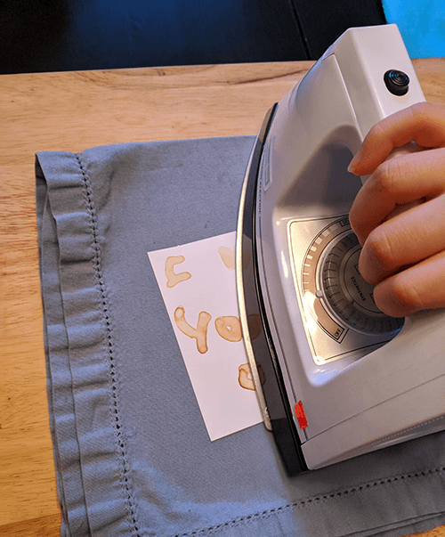 Iron being applied to a piece of paper on which an invisible ink has been used