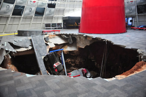 A large sinkhole in the center of a car museum showroom