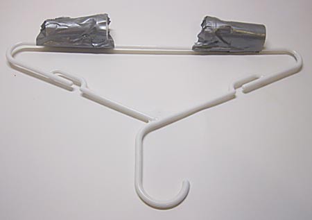 Two film canisters taped to the long edge of a clothes hanger