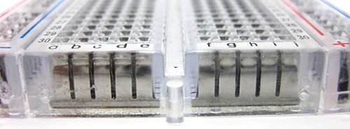 Rows of spring clips are visible inside a transparent breadboard