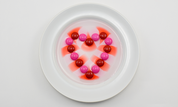 Pink and red candies in a heart shape in a dish of water for diffusion activity
