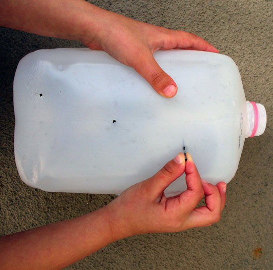 A nail is inserted into the side of an empty milk jug