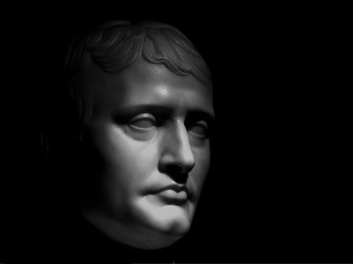 Light reflects onto the face of a statue in a dark room