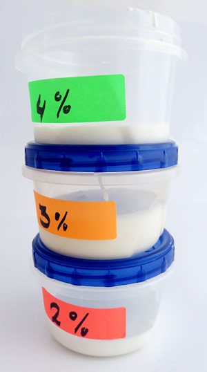 A stack of three plastic containers contain different concentrations of a white liquid mixture