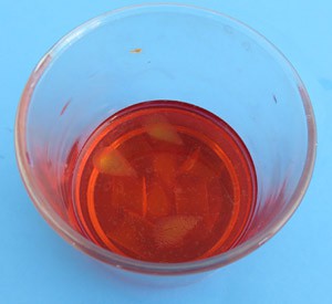Yellow Jell-O cubes in plastic cup filled with red liquid