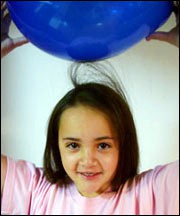 Strands of hair on a child's head rise towards a blue balloon