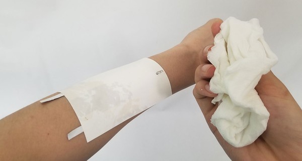 Using a damp towel to wet the temporary tattoo backing. 