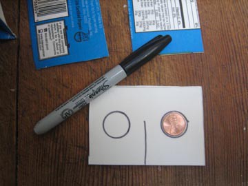 The shape of a penny is traced on the left and right side of a cardboard rectangle