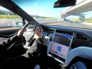 Person driving a Tesla plug-in electric car Model X on a motorway