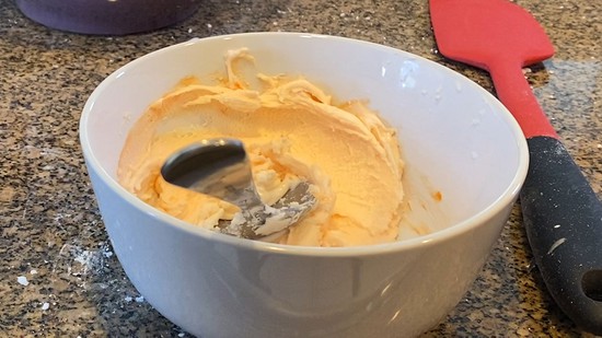 A bowl of yellow royal icing. The icing is so thick and holds its shape.  