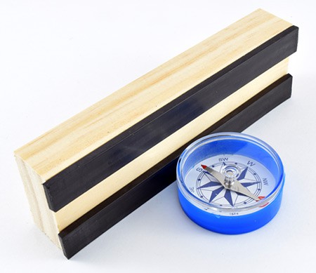A compass next to two magnetic strips on a wooden block