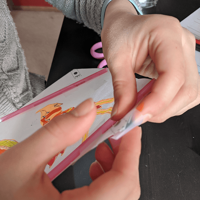 Student tapes straw supports to homemade paper kite