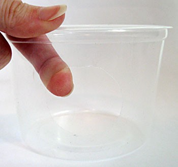 A circular hole is cut on the side of a small plastic cup