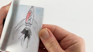 Person flipping through a flip book, landing on a page with a rocket flying up.