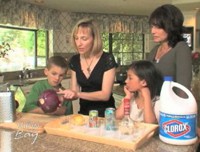 Two women and two children perform a science experiment in the kitchen