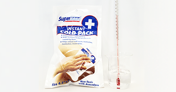 Cold-pack product next to a beaker with a solution and a thermometer
