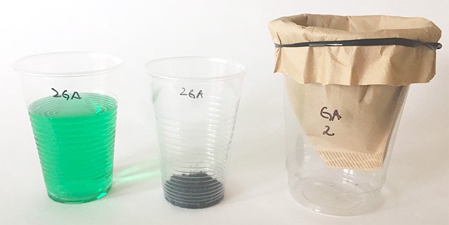 Three plastic cups contain a green dye solution, activated carbon, and a paper coffee filter