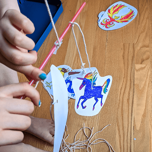 Student balancing a paper image hanging from a string on a straw