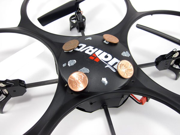 Four pennies are taped to the body of a toy drone