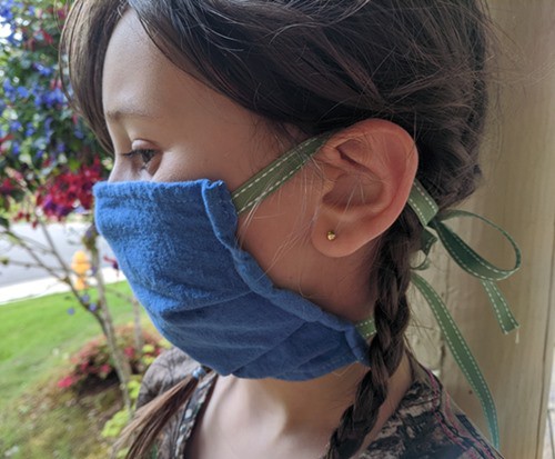 Girl wearing homemade cloth mask that fits over nose, mouth, and sits securely against side of face.