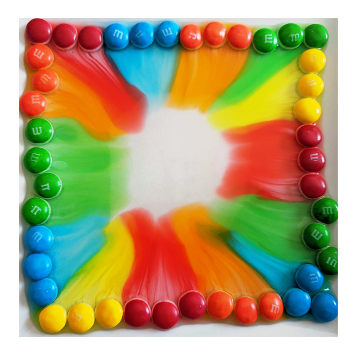 A ring of candies in a plate of water have created a colorful pattern as the candy coatings dissolved - Awesome Summer Science Experiments