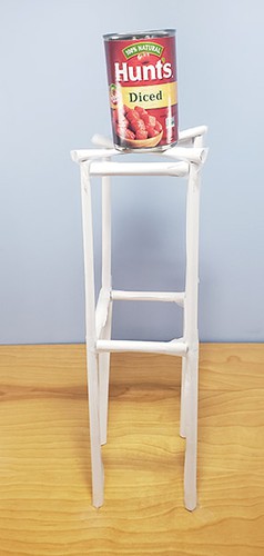 A paper tower with a rectangular frame and a can of beans at the top.
