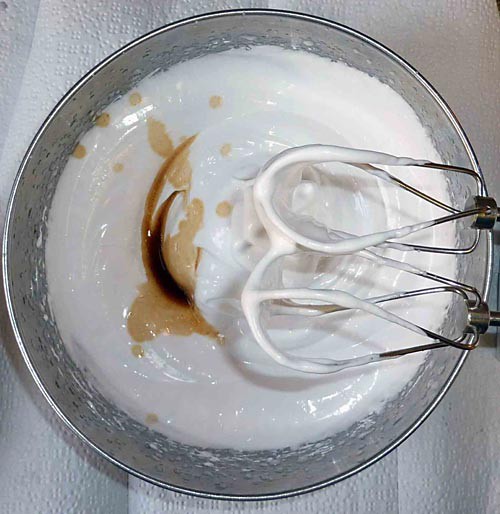 An egg beater mixes vanilla extract and marshmallow crème in a bowl