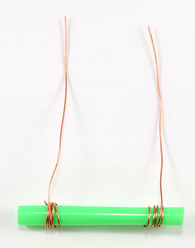 Two pieces of copper wire wrapped around opposite ends of a cut straw