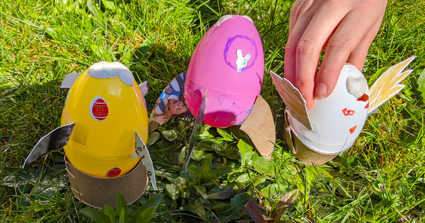 Child's hand placing an egg rocket that uses a baking soda chemical reaction next to two other egg rockets