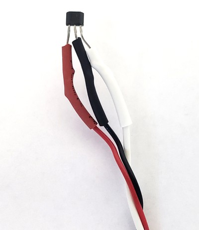 A hall effect sensor with red, black, and white wires soldered to its three pins with heat shrink tubing 