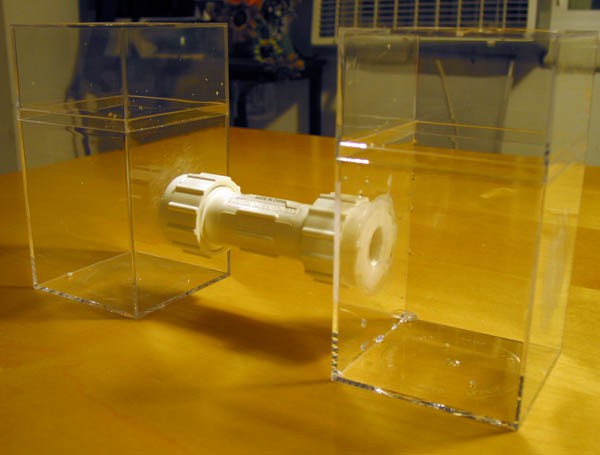 A plastic tube connects two plastic containers