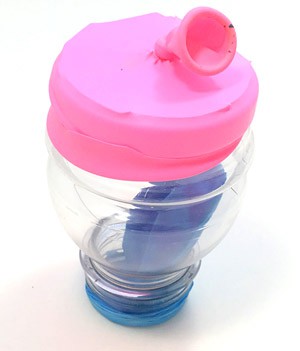 Cut off bottle resting on its small opening. A balloon covers the large opening.