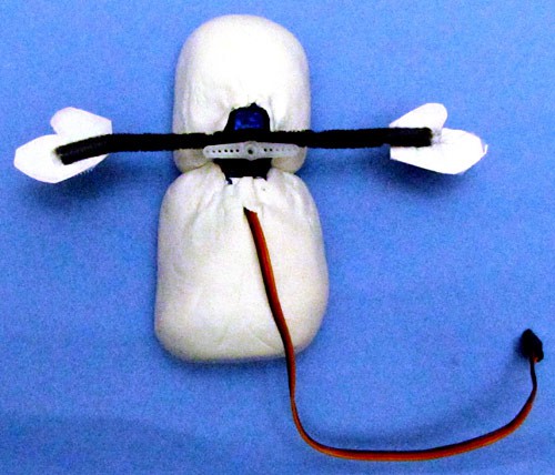 Model arms made of pipe cleaners are attached to a servo that is inserted into the back of a model clay figure