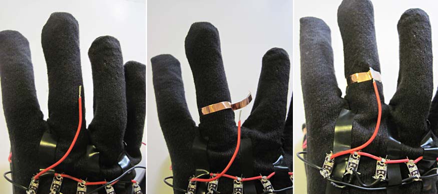Copper tape secures a red wire to the middle finger on a glove