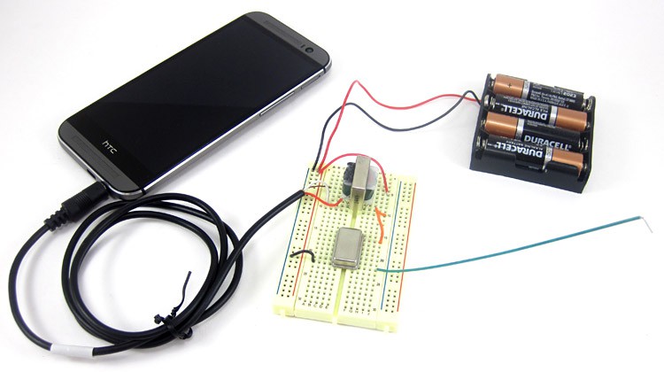 An audio jack connects a smartphone to a fully wired breadboard for an AM radio transmitter