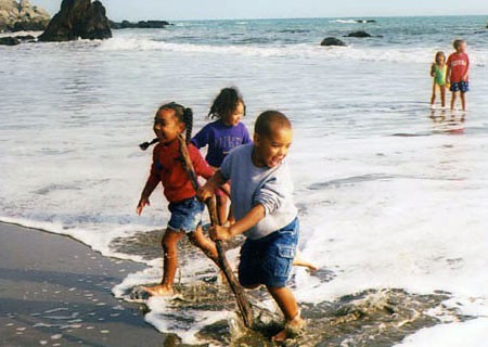 Photo of children running away from waves at a beach