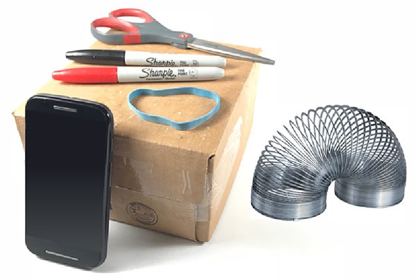 A smartphone, cardboard box, rubber band, scissors, two sharpies and a slinky