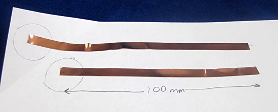 Two strips of copper tape of different lengths on a piece of paper