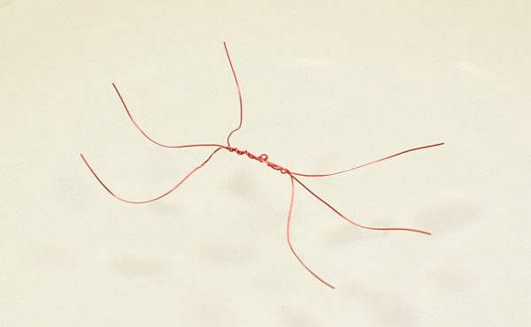 Three copper wires twisted together at the center form a bug with six legs